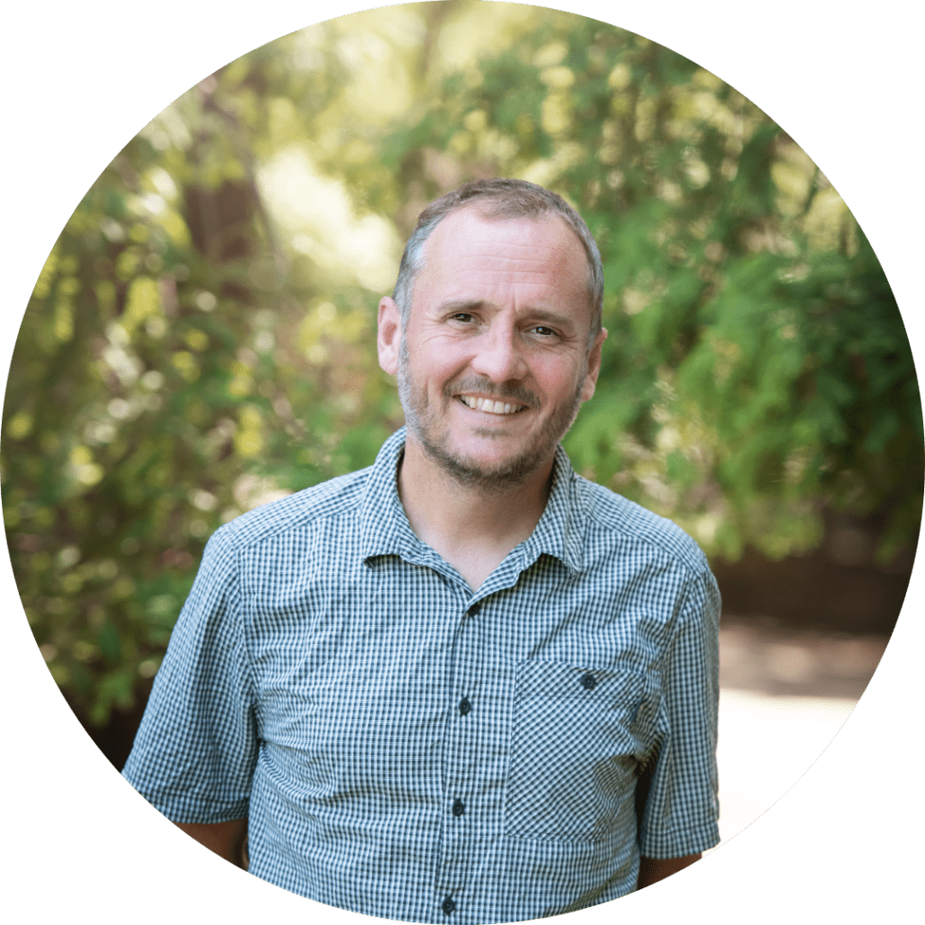 Dr Richard Young smiling against a bokeh background of trees