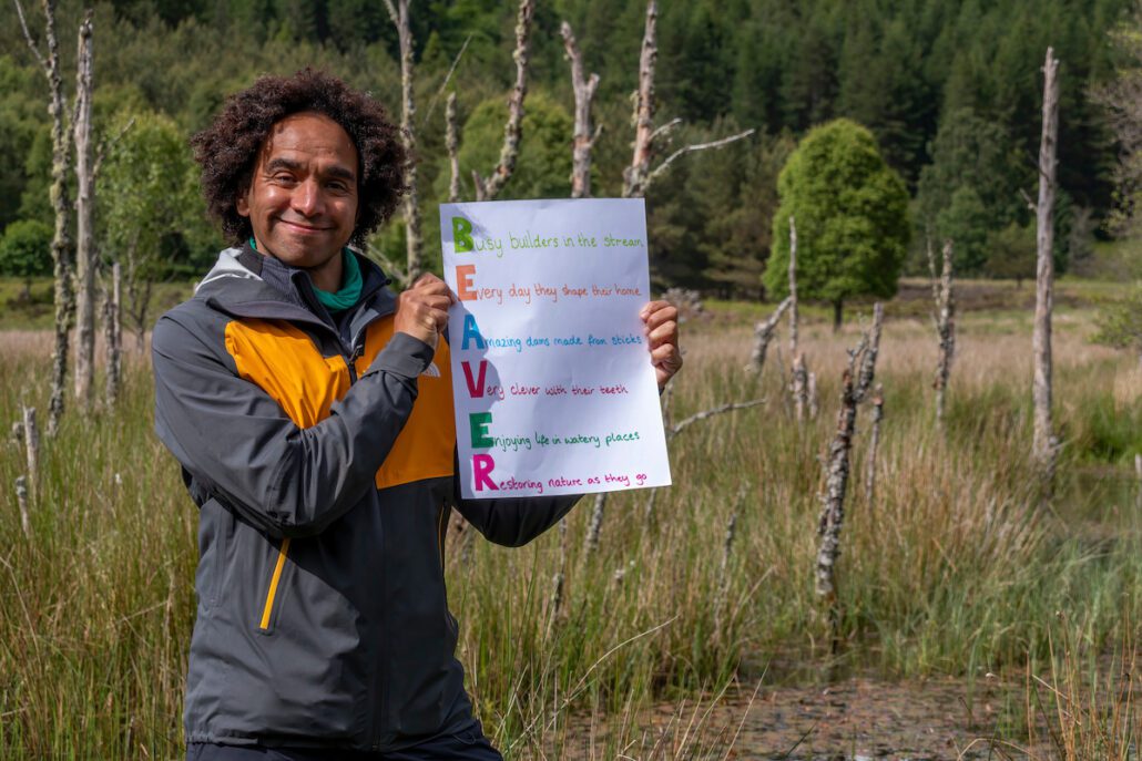 Joseph Coelho holding a poem in a beaver wetland
